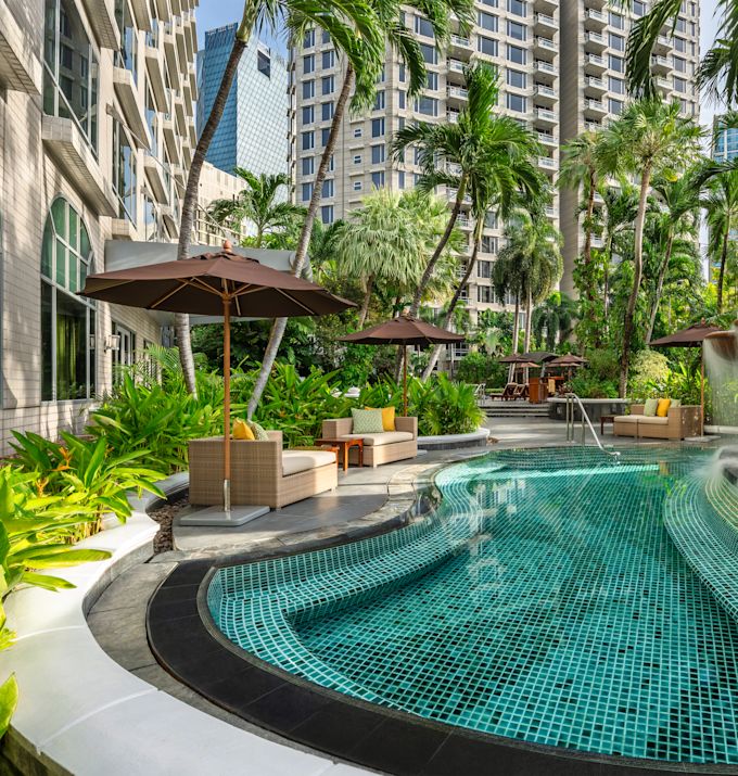 Outdoor Pool Area with Sitting Area under Umbrellas and Palm Trees
