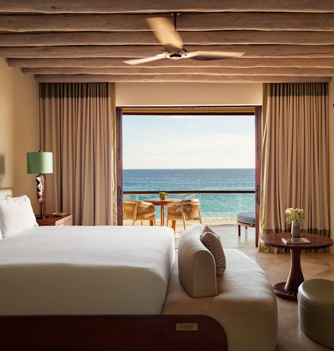 Cama y área de estar en la terraza de una suite con vista al mar