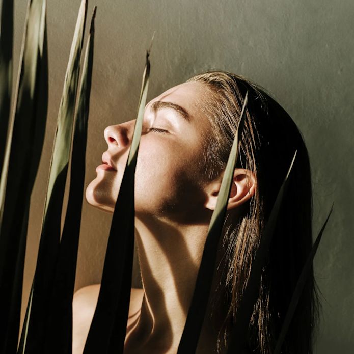 Frauen mit Pflanze und Schatten über ihrem Gesicht