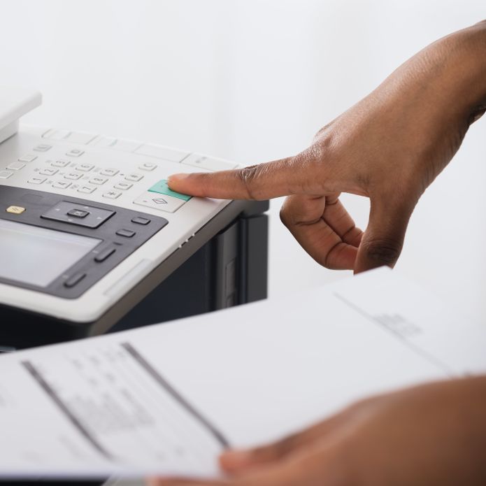 Closeup of hand pressing a button on a photocopier