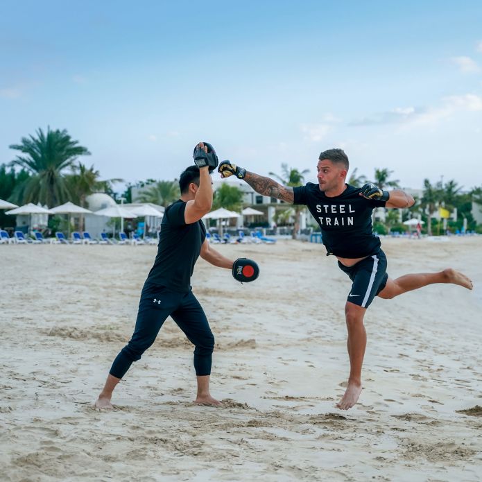 2 men doing a boxing workout on beach