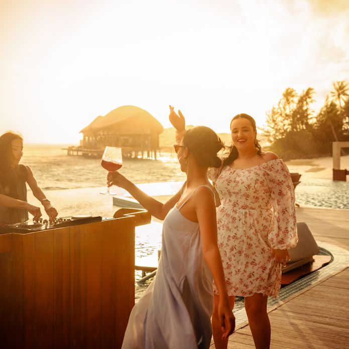 Two Women Drinking and Having Fun at Aura Pool Bar on the Beach at Sunset