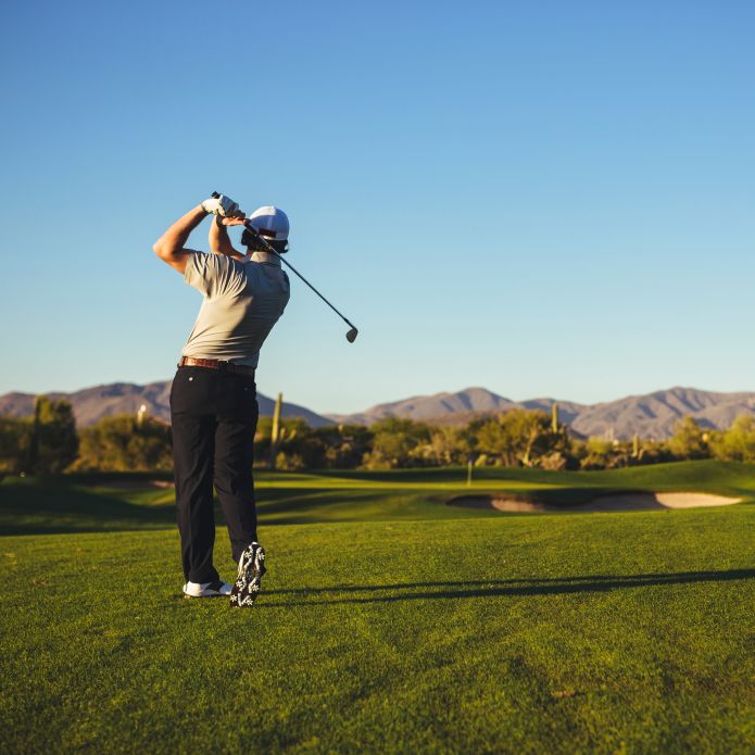 Mężczyzna pośrodku golfa waha się na polu golfowym