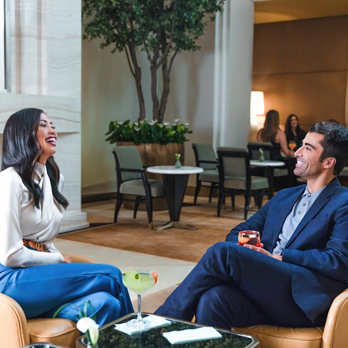 Pria dan wanita tersenyum saat mereka bersantai di area duduk lobi yang nyaman