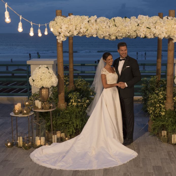 Bride and Groom Standing at Outdoor Wedding Setup with Ocean View