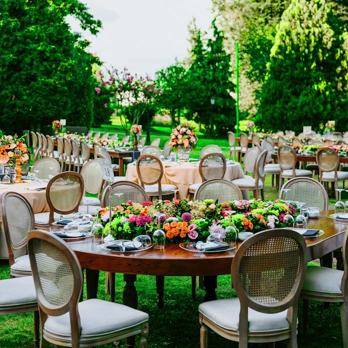 Outdoor wedding with round tables, chairs, trees and flowers