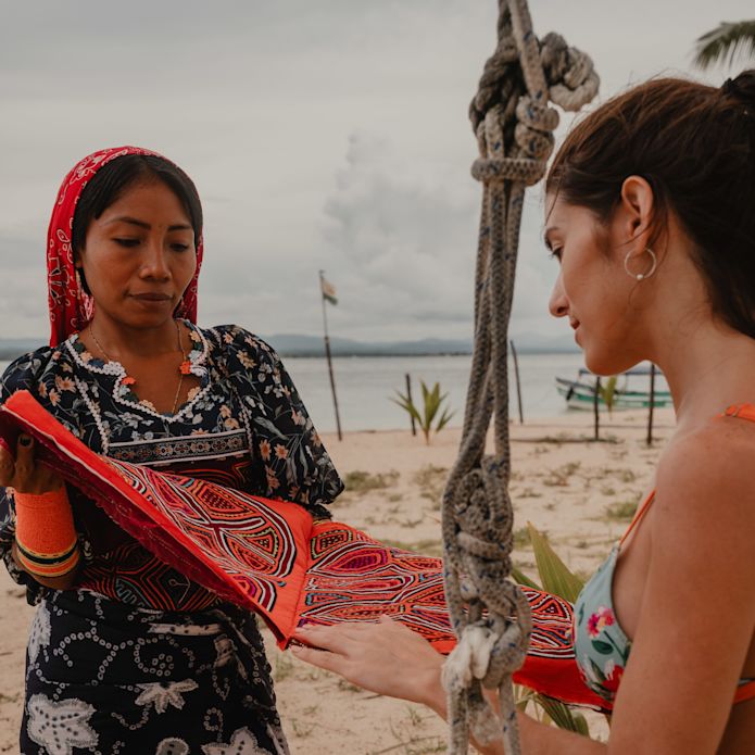 two women looking at material on the beach