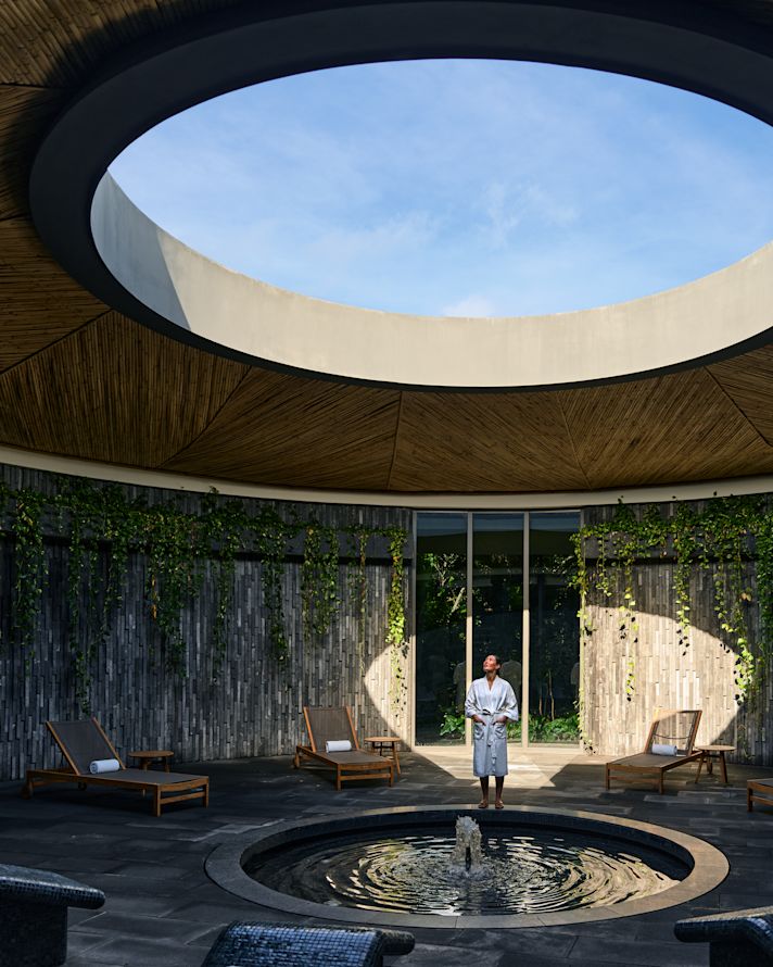 Duvarın dairesel bir kısmını aydınlatan ışık demetli spa alanı. Işıkta duran bir kişi