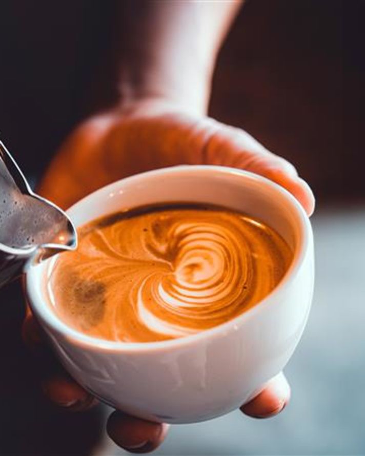 Person som häller kaffe i koppen och skapar design