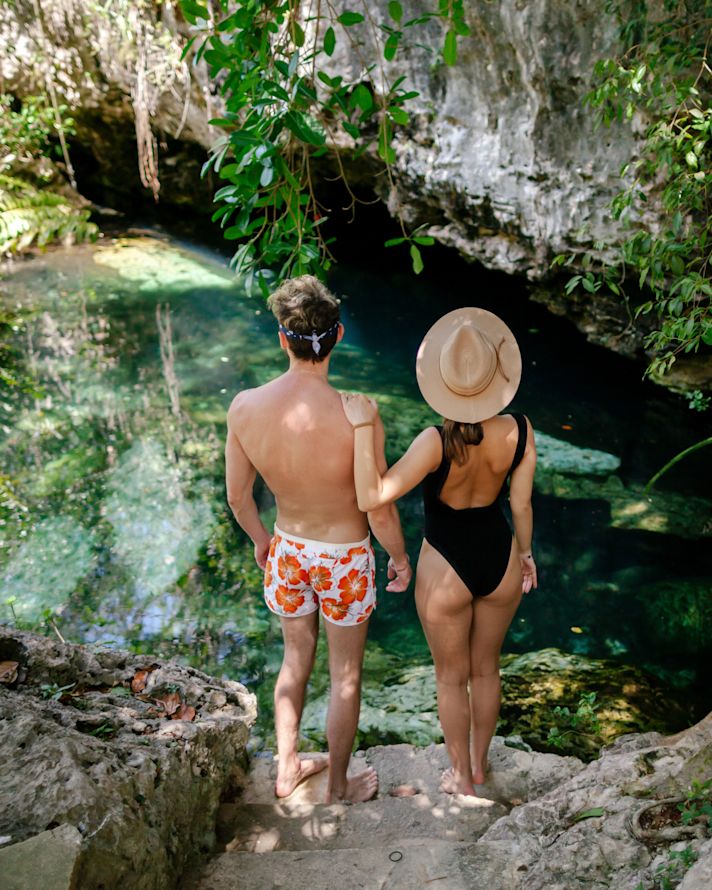 man and woman standing on rocks overlooking water