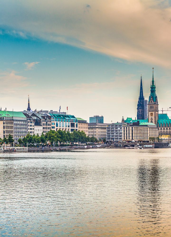 Vista spigolosa del lungofiume di Amburgo con vari edifici sul lungofiume e due vogatori sul fiume