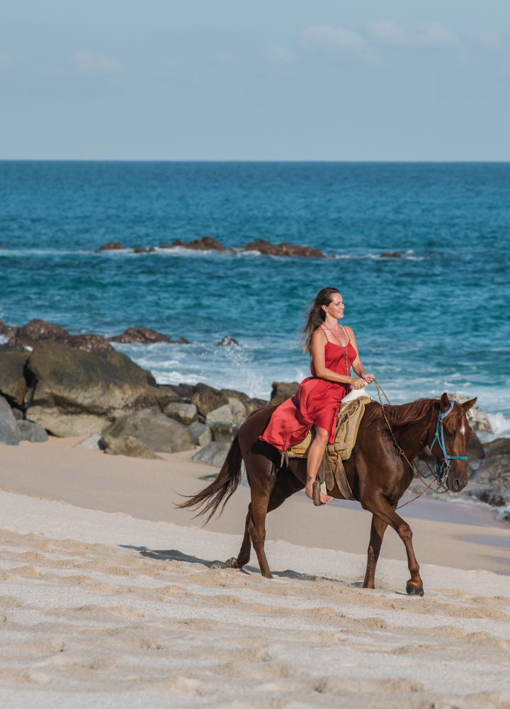 une femme faisant du cheval sur la plage