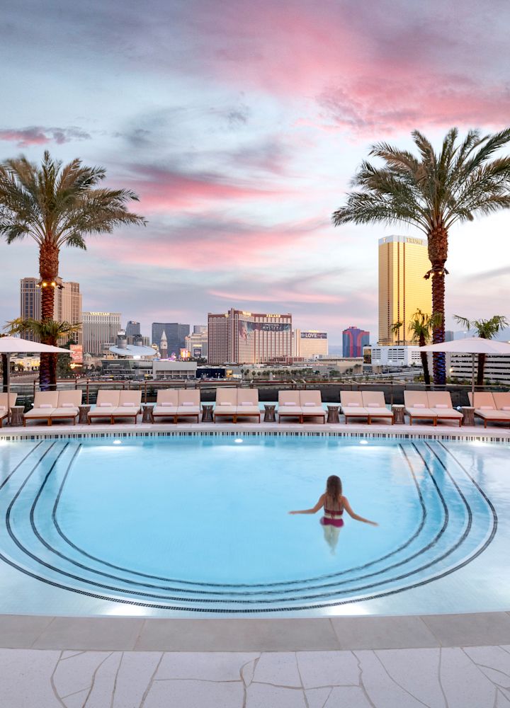 Femme debout dans la piscine avec des palmiers encadrant la vue sur la ville
