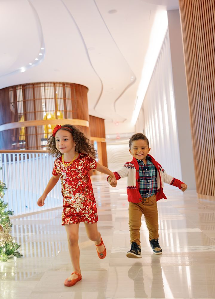Kids Running in the Lobby Decorated with a Christmas Tree to Celebrate the Holidays