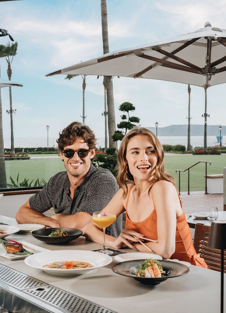 แขกที่รับประทานอาหารที่บริเวณบาร์ของ Nobu del Coronado วิวสนามหญ้าและน้ํา