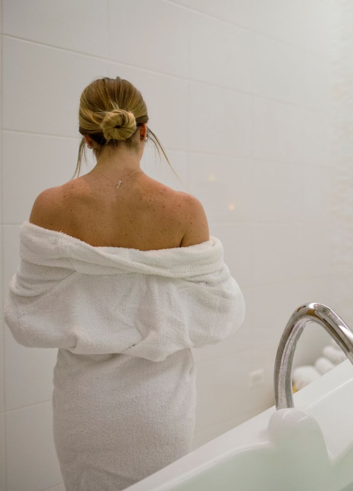 Woman in robe standing near bath