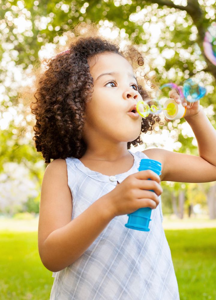 Giovane ragazza che soffia le bolle nel parco