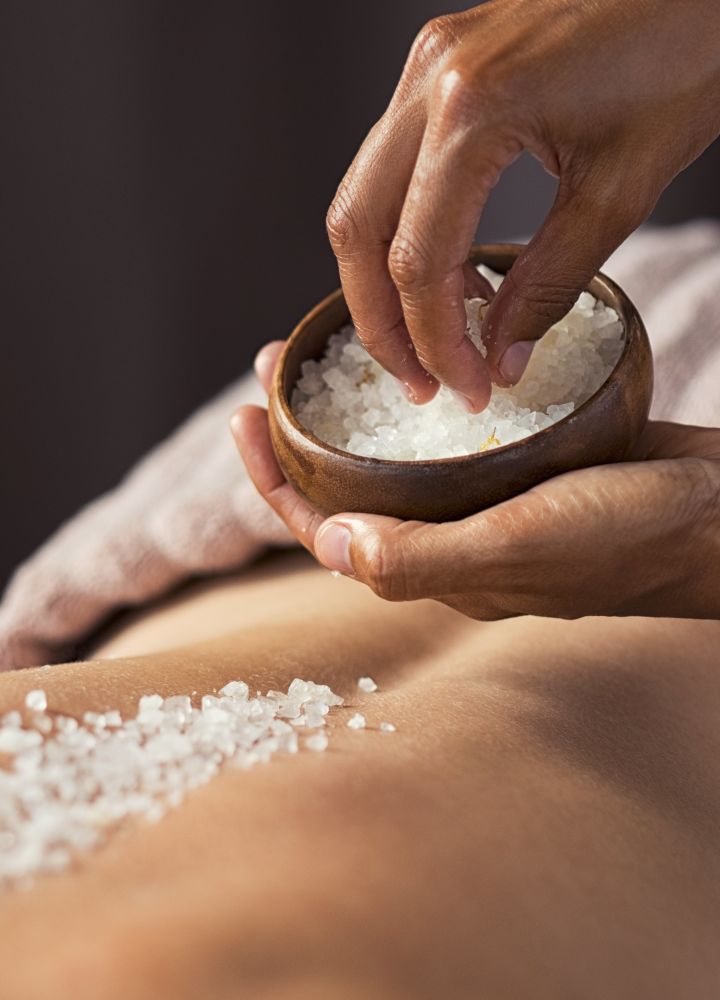 Salt crystals being placed on woman's back in spa