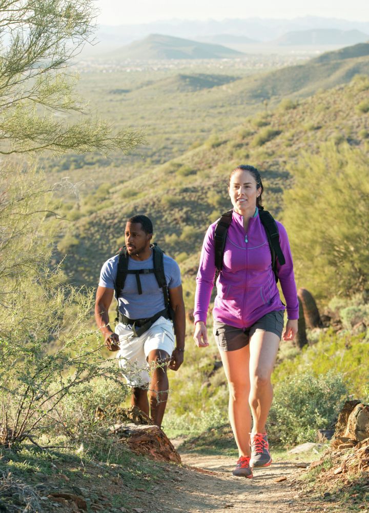 Young couple hiking outdoors on a trail at Phoenix Sonoran Preserve in Phoenix, Arizona.