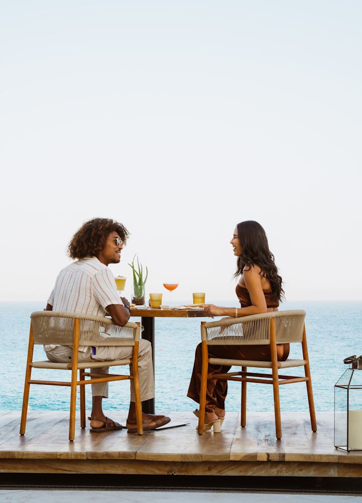 Paar am Esstisch im Freien mit Blick auf den Strand