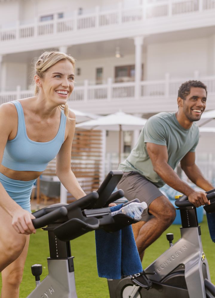 man and woman outdoors using stationary bikes