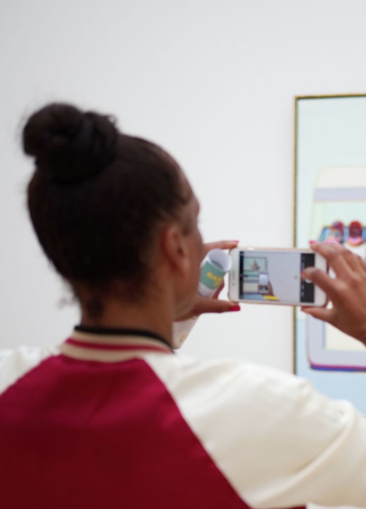 Två kvinnor tar bilder på konsttelefoner på en vägg