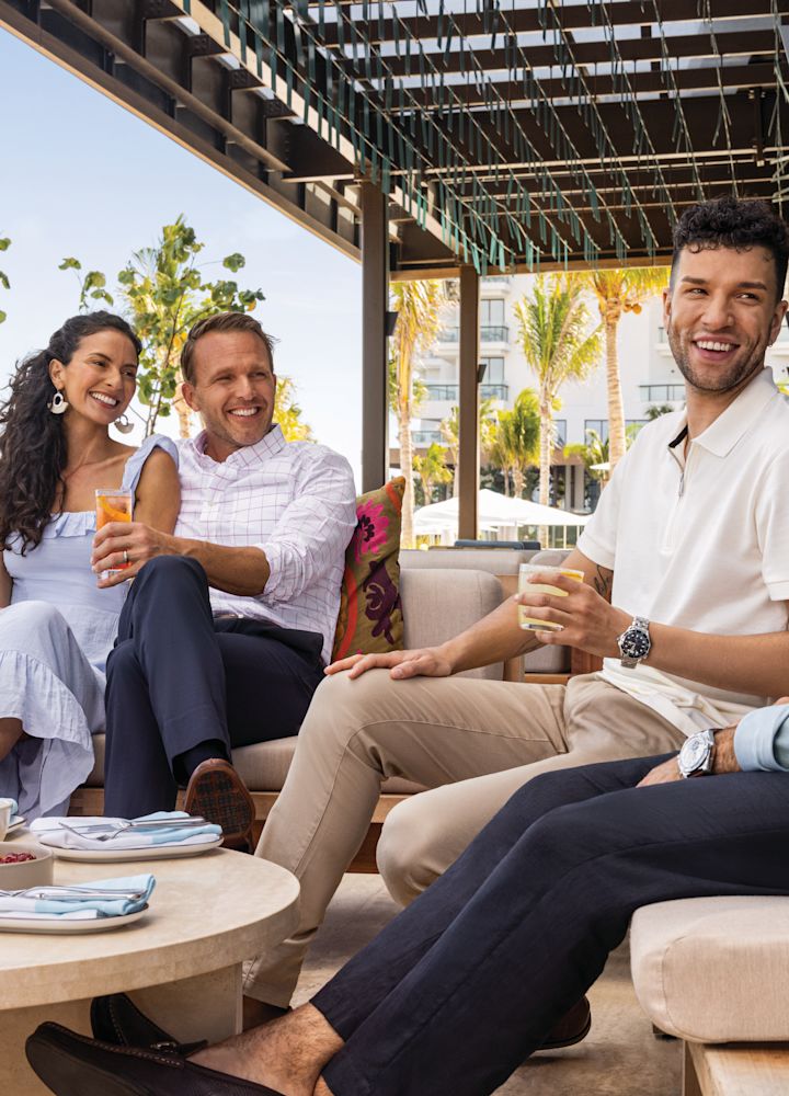 friends enjoying drinks and food at hotels outdoor restaurant by the beach