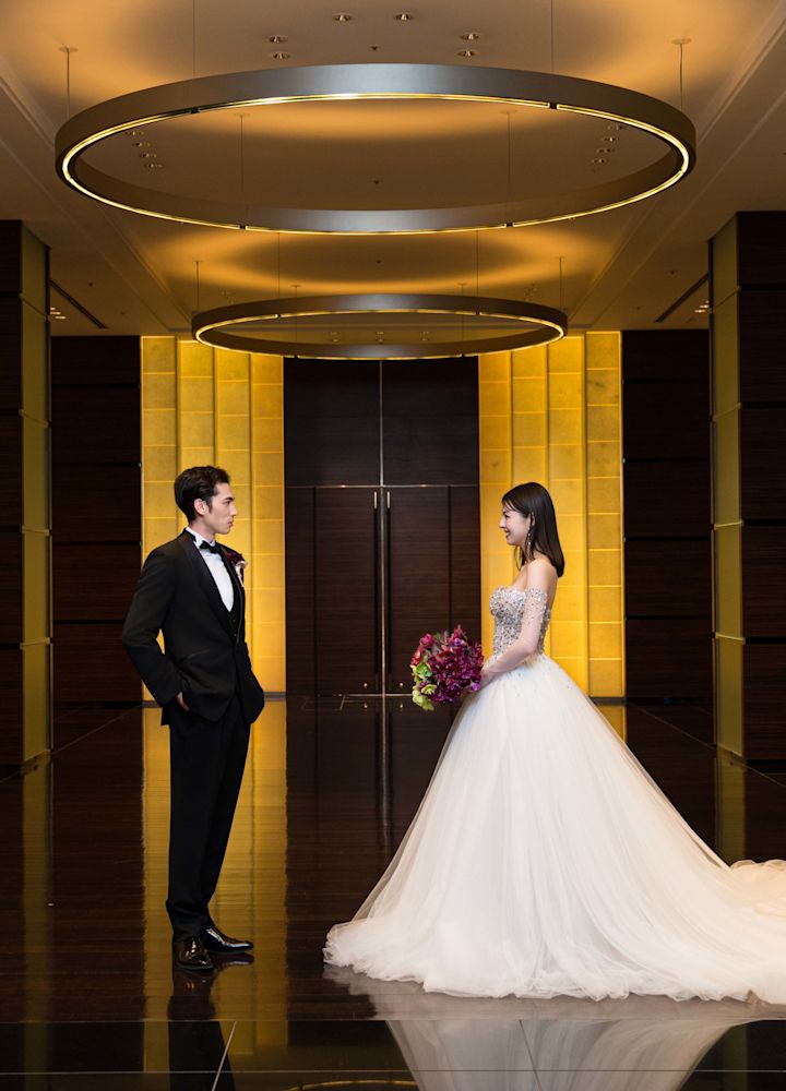 Un couple pose pour une photo vêtue d'un smoking et d'une robe de mariage