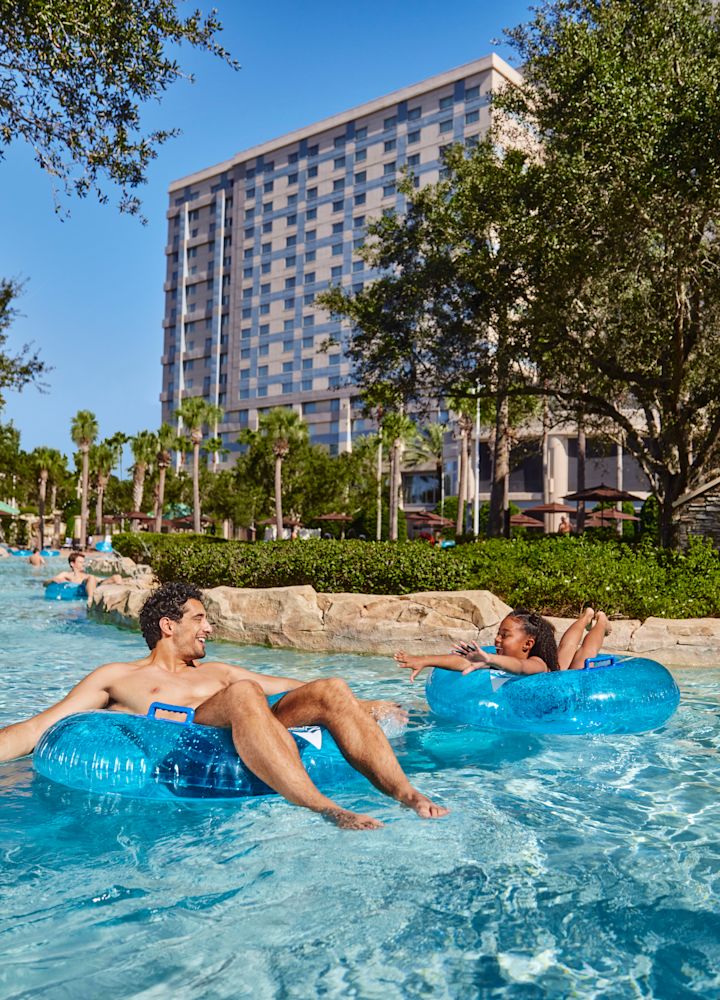 Un homme et une jeune fille sur des tubes en caoutchouc dans la piscine extérieure