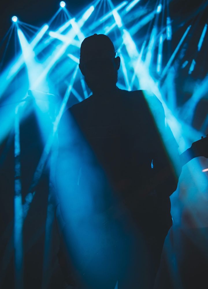 Silhouette of guitarist amongst streams of blue light