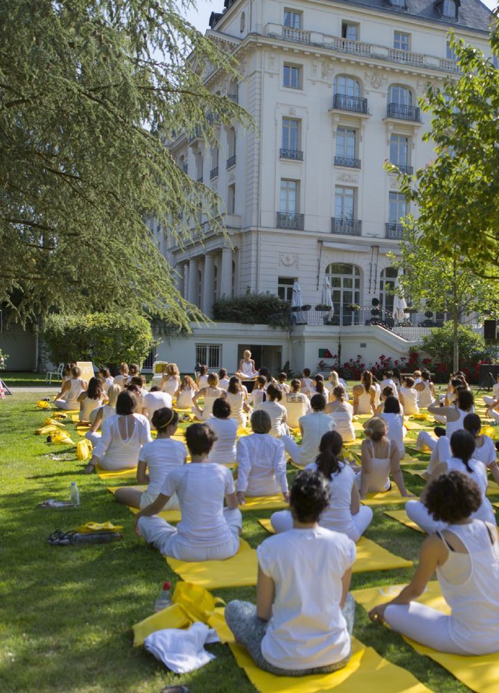 a group of people practicing yoga on lawn of the hotel