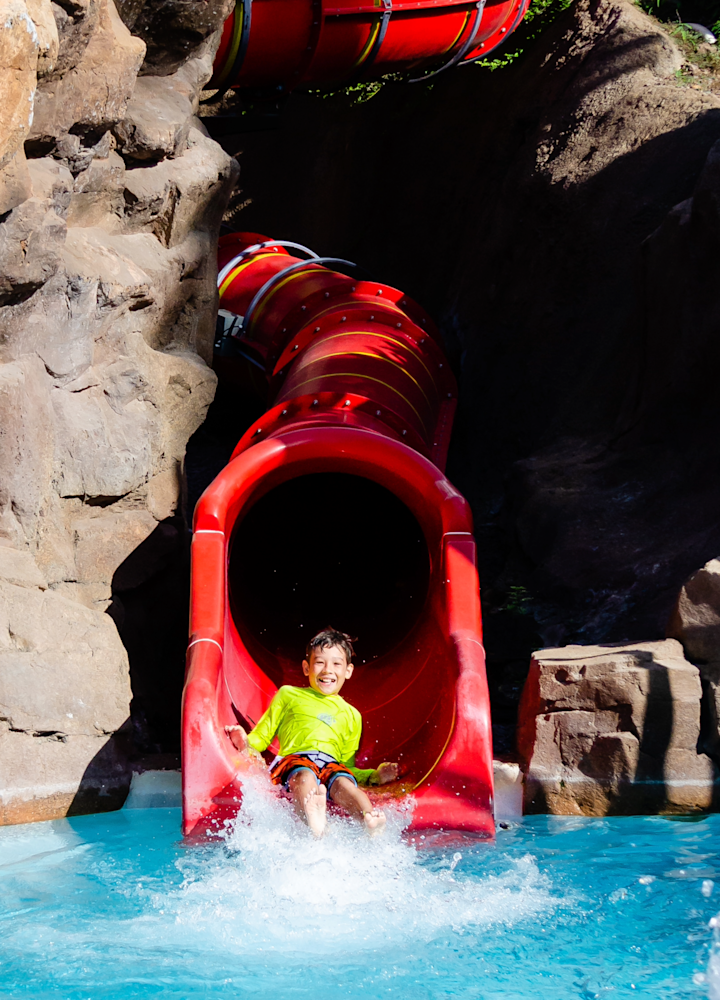 Niño en un tobogán acuático de la piscina