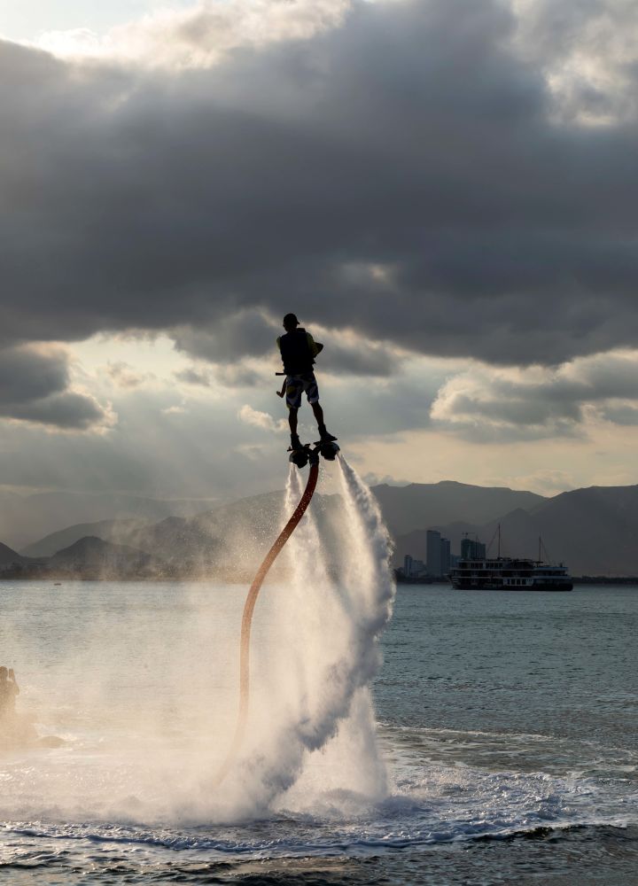 Person using a water jetpack to fly above ocean