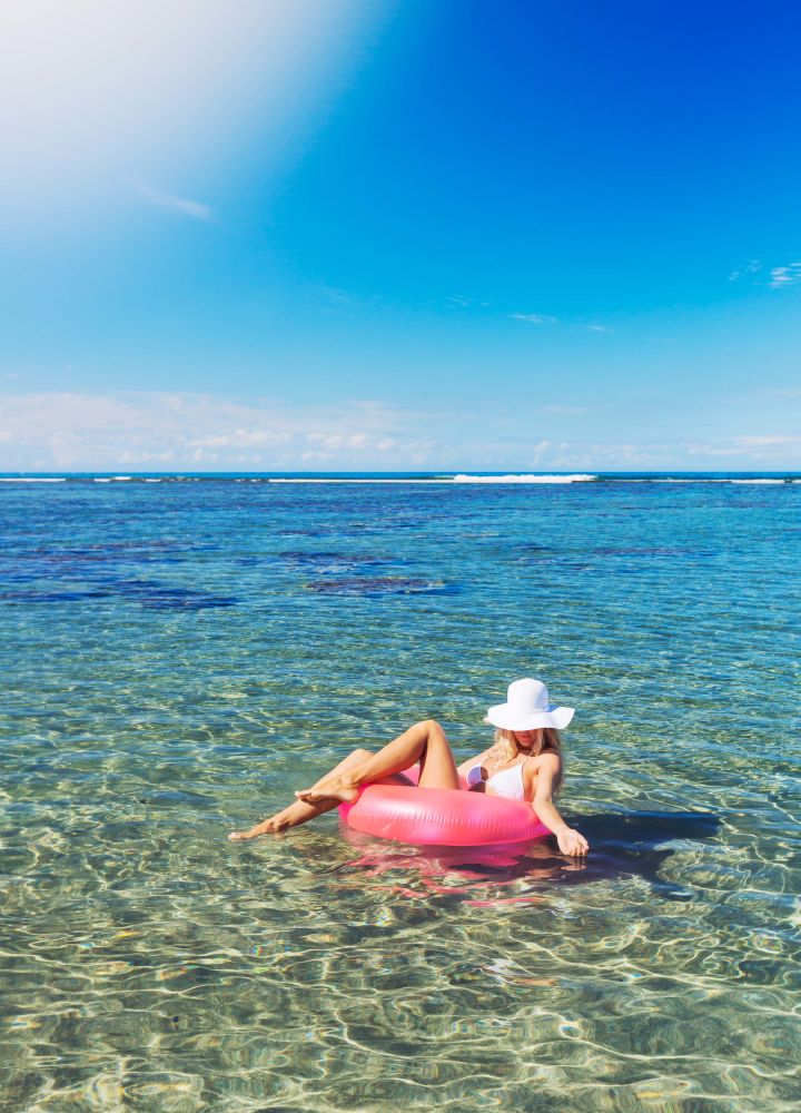 Woman in hat floating on an inflatable in the ocean