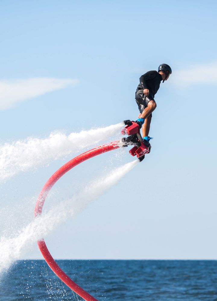Person using a water jetpack to fly above ocean