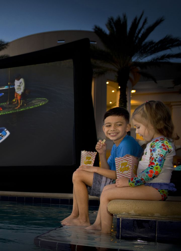 Kids Enjoying a Movie by the Pool Area in the Evening