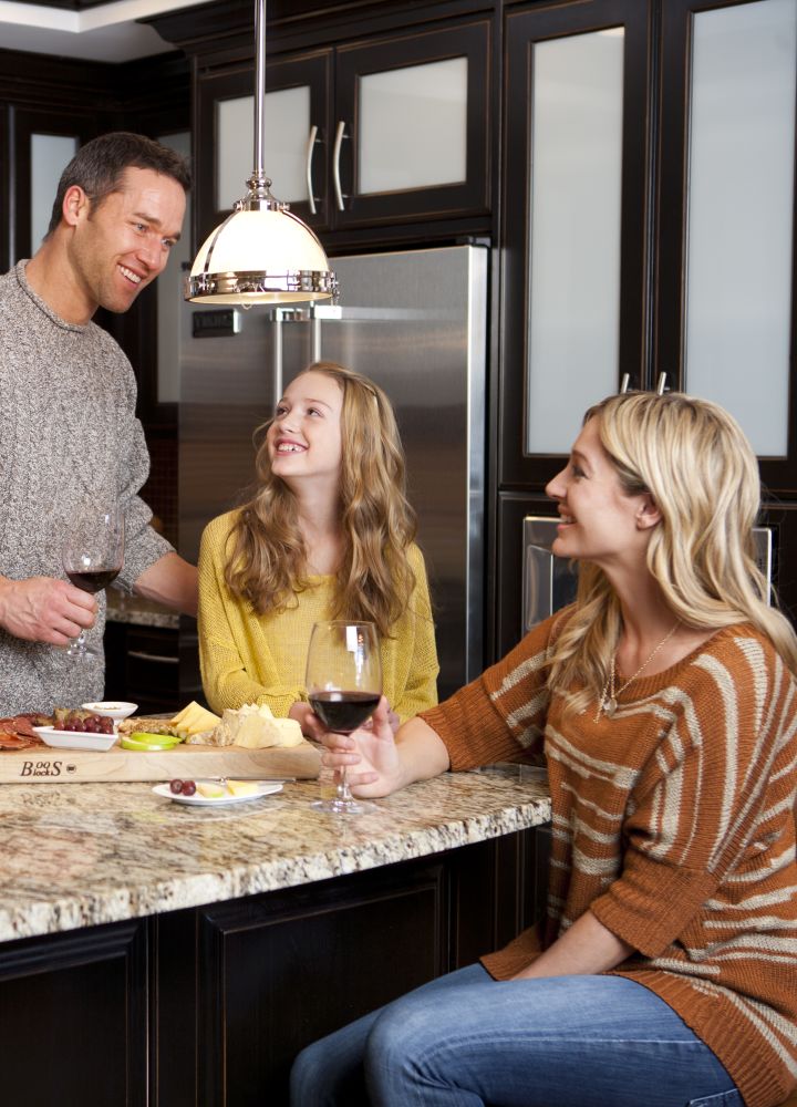 Family of three enjoying food and drinks in the kitchen of the three bedroom whirlpool suite