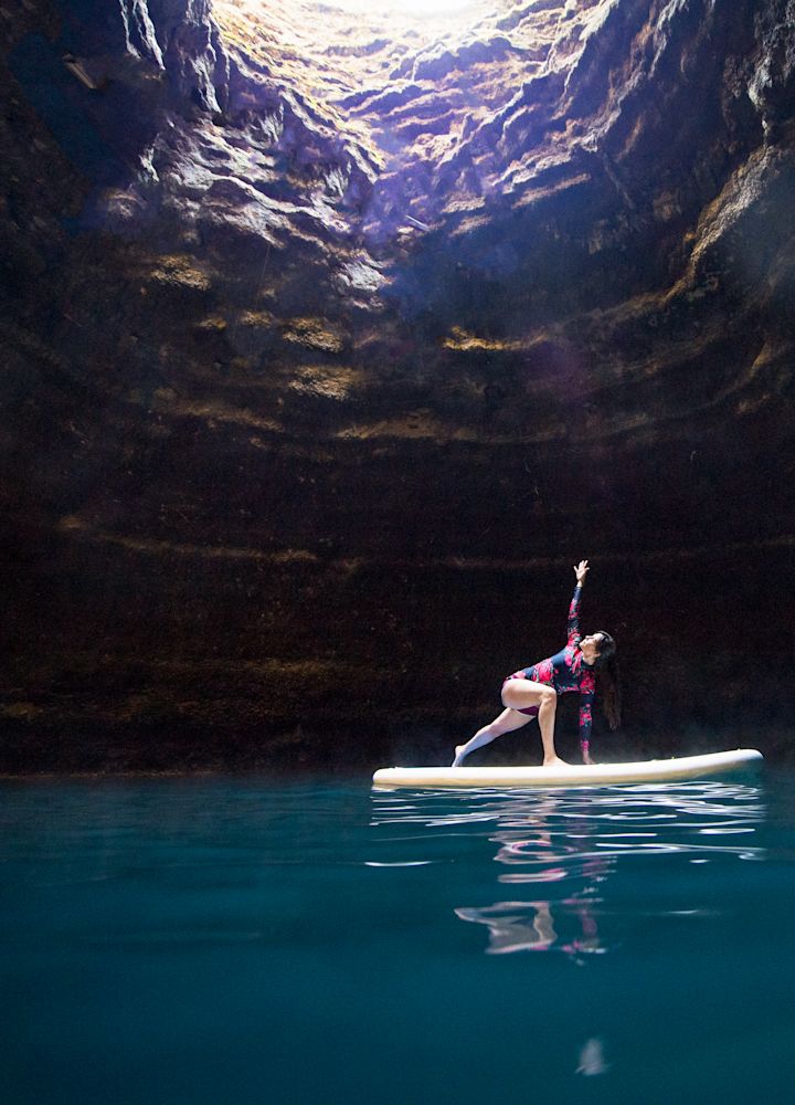 a Woman Stretching on a Board on the Water in a Cave