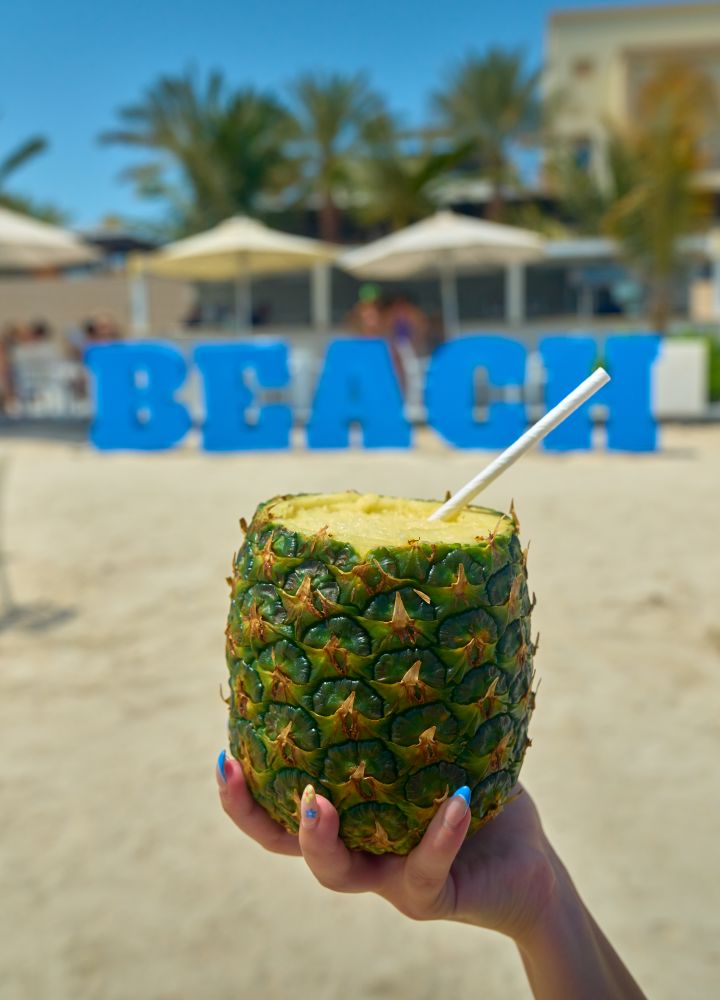 Closeup of a hand holding a pineapple containing a cocktail