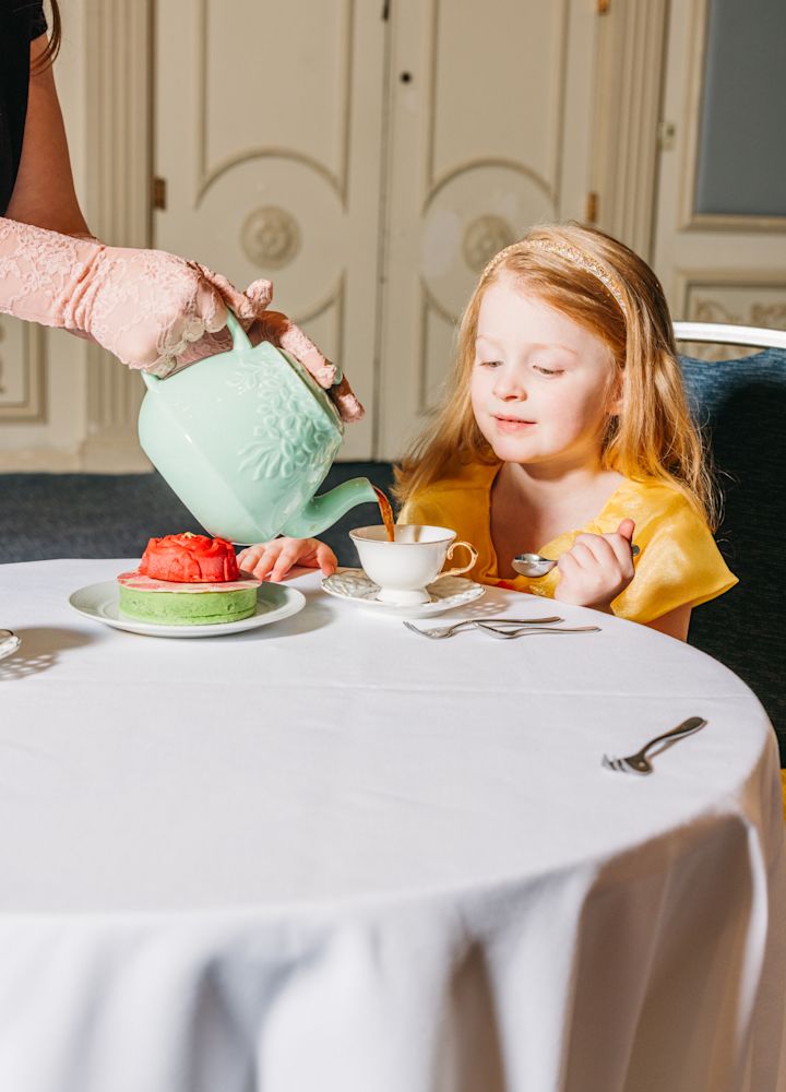 Kellner gießt Tee in eine Tasse für ein Mädchen in einem Restaurant