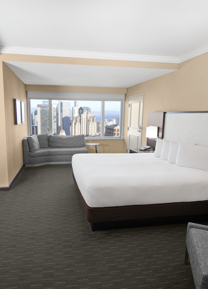 A king bed and sofa bed with a skyline view in the junior suite.