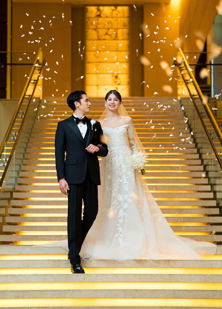 Un couple marié dans un escalier entouré de pétales de fleurs en chute