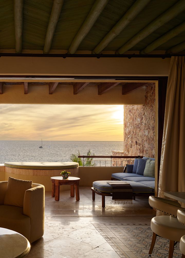 Área de estar em um terraço da suíte com vista para o mar ao pôr do sol