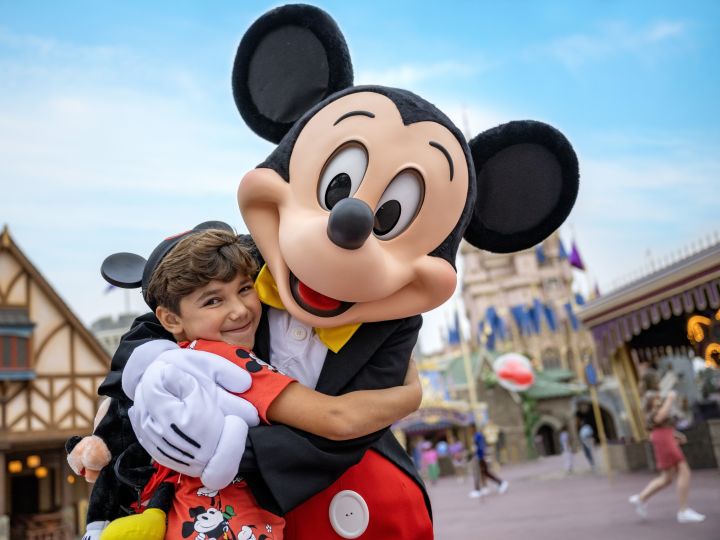 un niño abrazando a Micky Mouse en Disney World