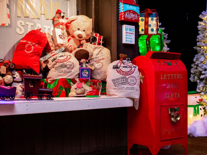 red mailbox next to table of toys, Christmas tree in the back