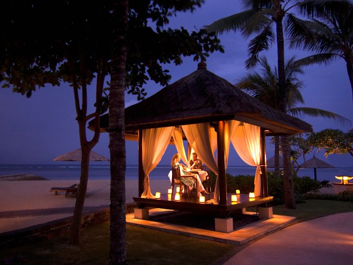 Couple enjoying a romantic dinner on a gazebo at the Eight Degrees South Restaurant Bale restaurant with beach view