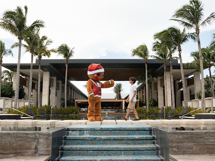 Person, die ein Weihnachts-Outfit trägt, und Junge, die auf dem Außenbereich des Hotels spazieren geht