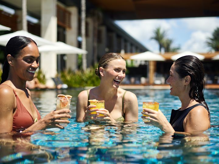 Skupina lidí, kteří mají nápoje v hotelovém bazénu