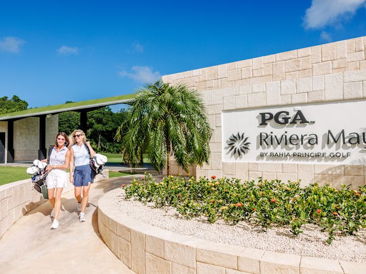 Două femei merg pe jos la intrarea pe PGA Riviera Maya de Bahia Principe Golf