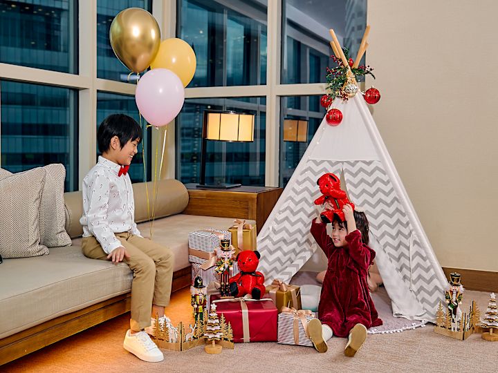Boy and Girl Playing with Red Teddy Bears in a Guest Room with a Tent during the Holidays